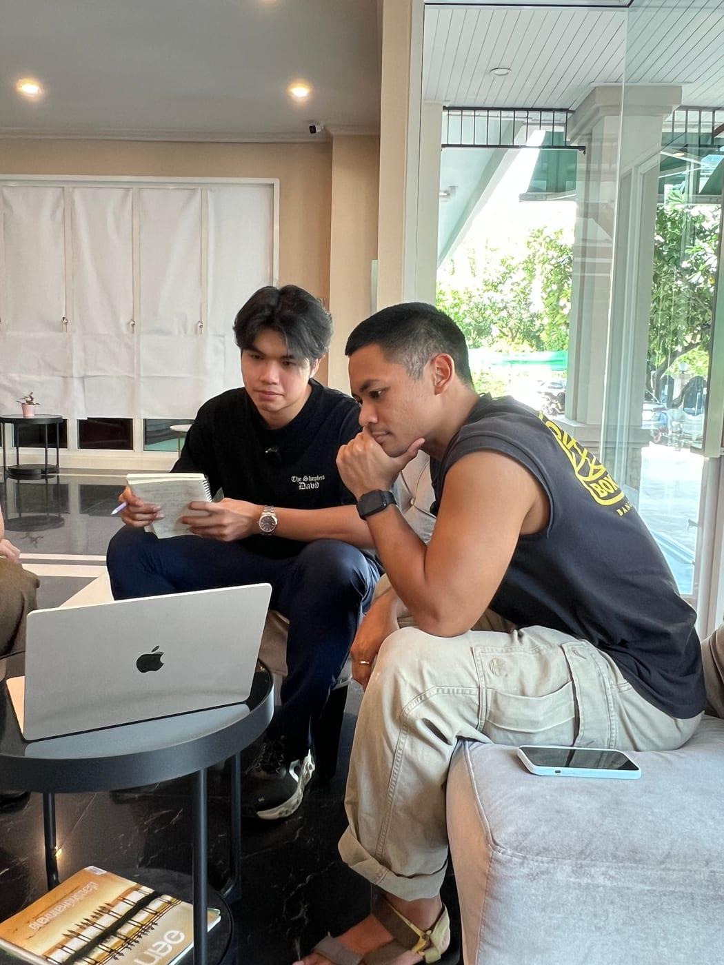 ทีมงานสองคนนั่งดูโน้ตบุ๊กด้วยกัน คนหนึ่งจดบันทึกลงสมุด ระหว่างคุยทำความเข้าใจธุรกิจของลูกค้า